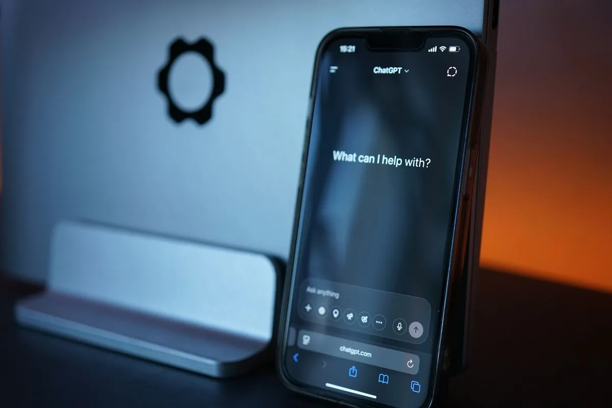 Smartfón so zadávacou obrazovkou ChatGPT vedľa počítačového monitora
